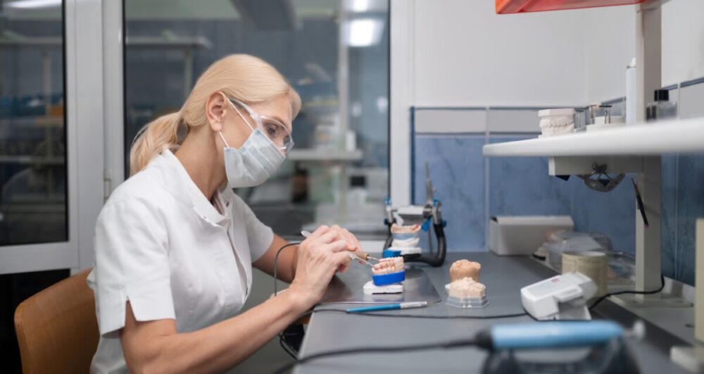 Concentrated dental technician sitting in her office constructing porcelain veneers for the patient